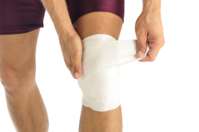 Athlete wrapping knee in bandage: RedLawList Accidents & Injuries Blog