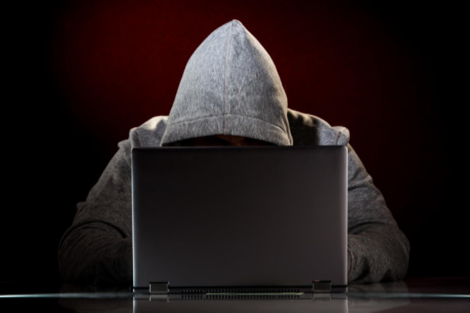 Hooded man at computer: RedLawList Criminal Law Blog