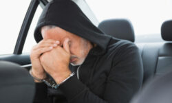 Hooded man with head in hands: RedLawList Criminal Defense Blog