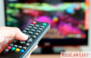 hand holding a remote in front of a blurry tv screen