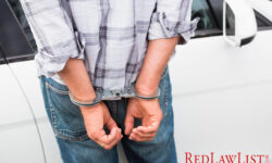 man in handcuffs in front of car